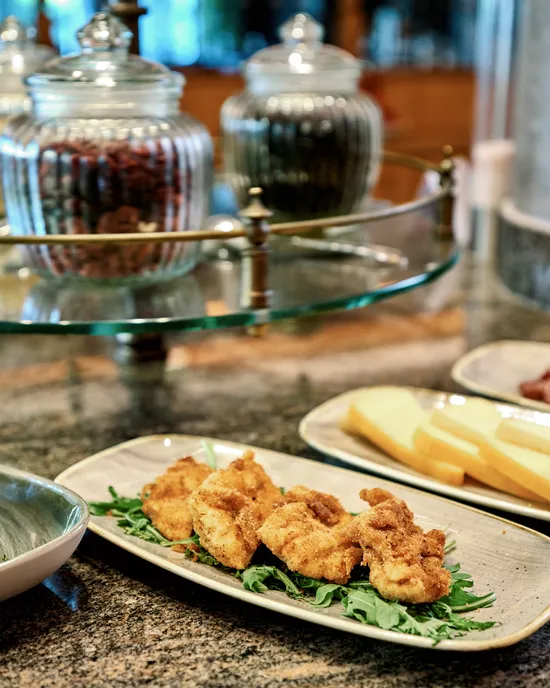 Antipasti assortiti con fette di formaggio, bocconcini fritti e formaggio morbido fresco su tavolo da pranzo